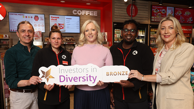 Circle K staff members pose inside a convenience store, holding a sign that reads 'Investors in Diversity Bronze'.
