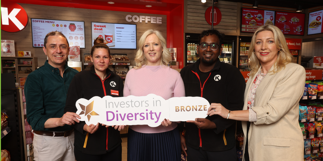 Circle K staff members pose inside a convenience store, holding a sign that reads 'Investors in Diversity Bronze'
