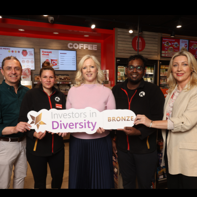 Circle K staff members pose inside a convenience store, holding a sign that reads 'Investors in Diversity Bronze'