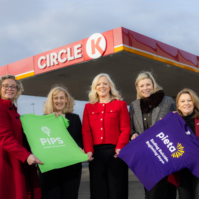 Representatives of Circle K and Pieta holding t-shirts of Pieta and PIPS, posing in front of a CK station