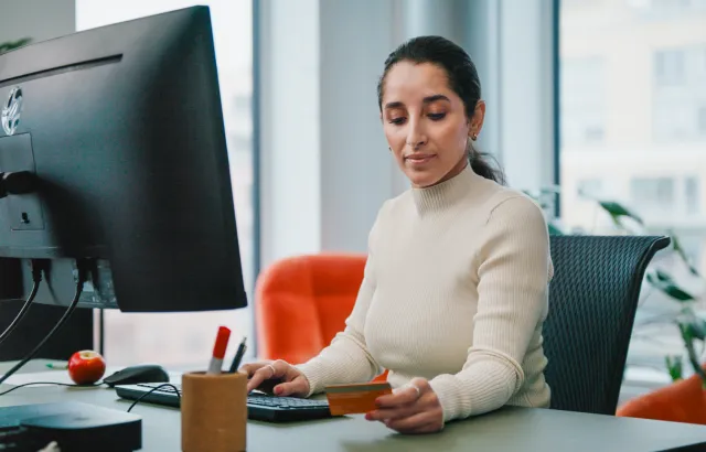 Woman in an office working on her computer, while checking her Circle K fuel card
