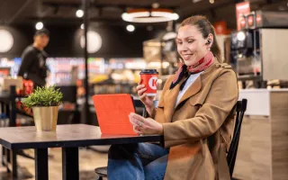 A woman sitting at a table with a computer and a cup of coffee on a CK station