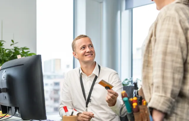 Man happily showing Circle K fuel card to another person in the office